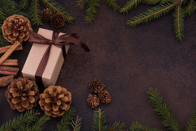 Foto regalo sullo sfondo di un albero di natale e coni