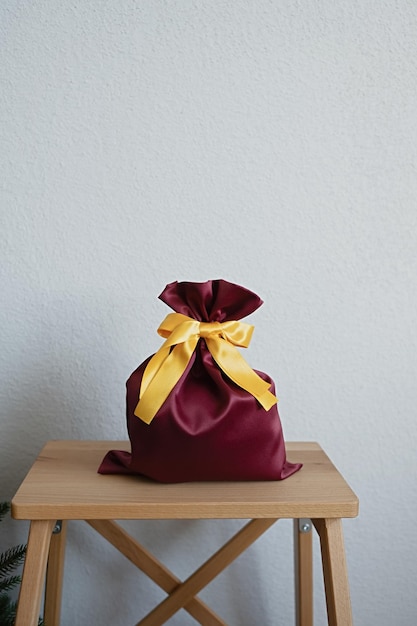 A gift bag stands on a stepladder by the Christmas tree