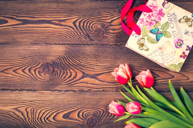 Gift bag and tulip flowers on a rustic table with space for text