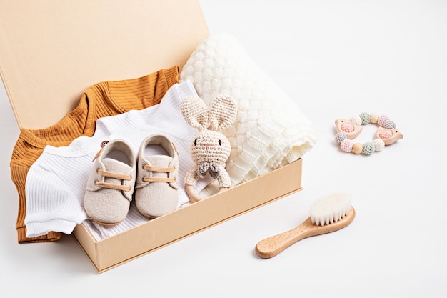 Photo gift basket with gender neutral baby garment and accessories. care box of organic newborn cotton clothes, fashion, branding, small business idea. flat lay, top view