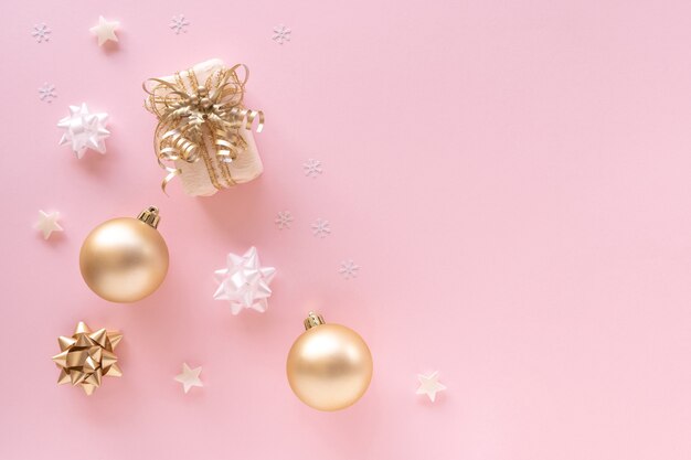 Gift, baubles, greeting card, golden decorations on pastel pink surface