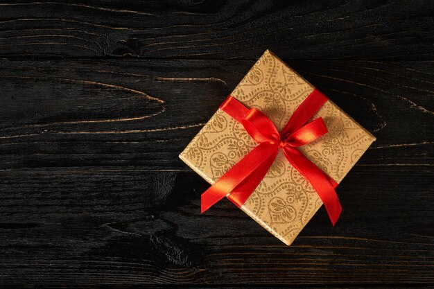 Gift birthday Christmas present concept gift box with red ribbon on dark wooden background