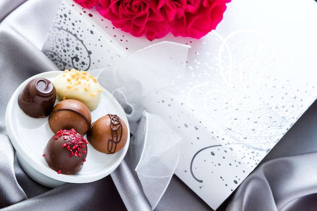 Gift box of assorted gourmet chocolate truffles on silver silk.