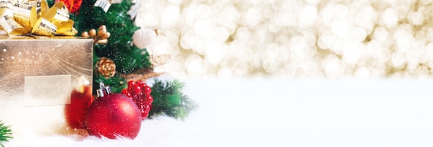 Gift box and ball decoration under christmas tree on white fir with bokeh background