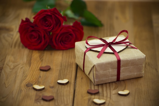 Gift box and a bouquet of roses on a wooden table