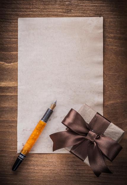 Foto confezione regalo penna stilografica in carta fiocco marrone su tavola di legno