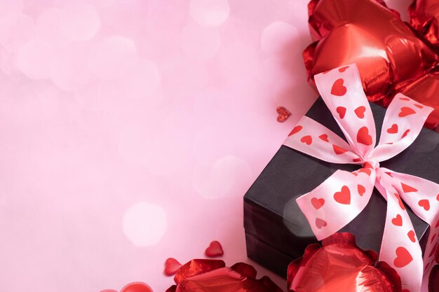 Gift box candels and red heart shape balloons on pink background with bokeh Valentines Day concept