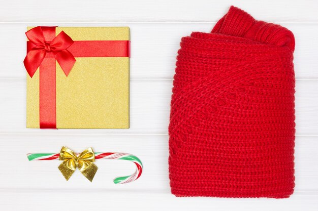 Gift box candy cane folded red sweater on white wooden boards flat lay christmas concept