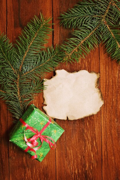 Confezione regalo e rami di albero di natale, fondo in legno