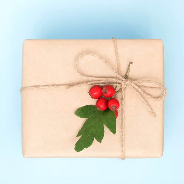 Gift box in craft packaging and with natural decor on a blue background, top view.