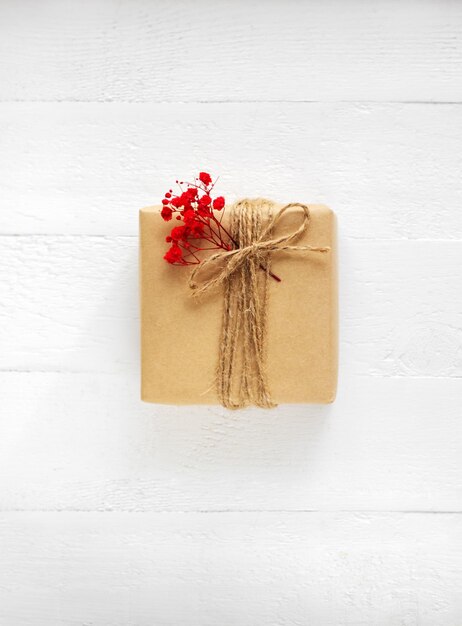 Gift box of craft paper with red flowers on the white wooden background Valentine39s Day Happy birthday