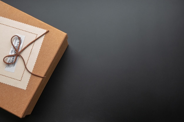 Gift box on a dark contrasted background, decorated with a textured bow