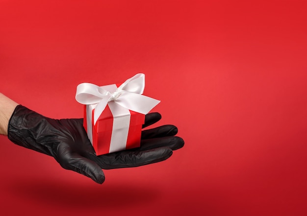 A gift box decorated with a bow lies in the palm of your hand in a black protective glove