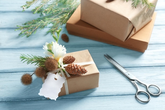 Gift box decorated with flowers and scissors on wooden background