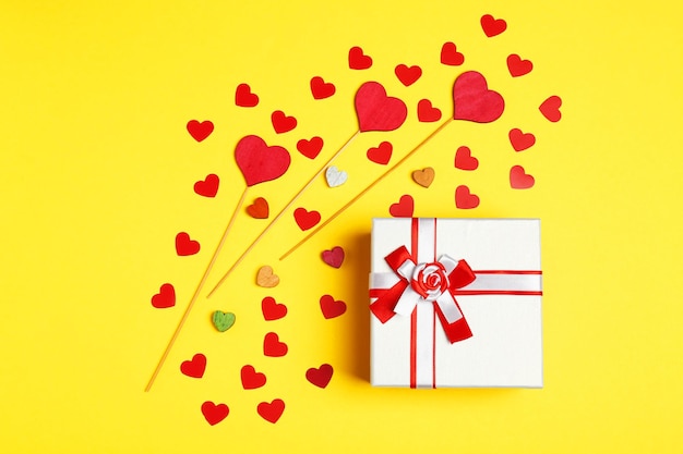 Gift box and decorative hearts on color background