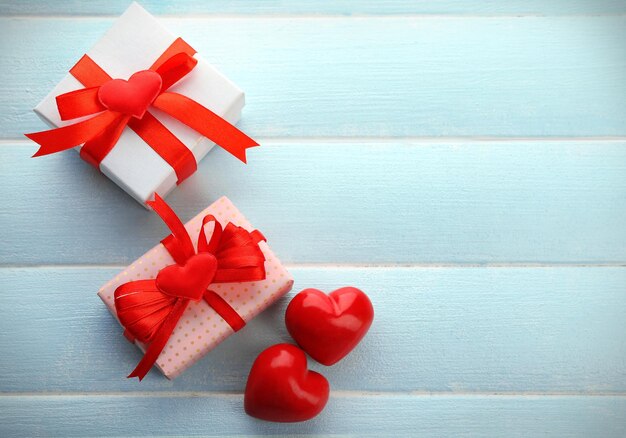 Gift box and decorative hearts on color wooden background