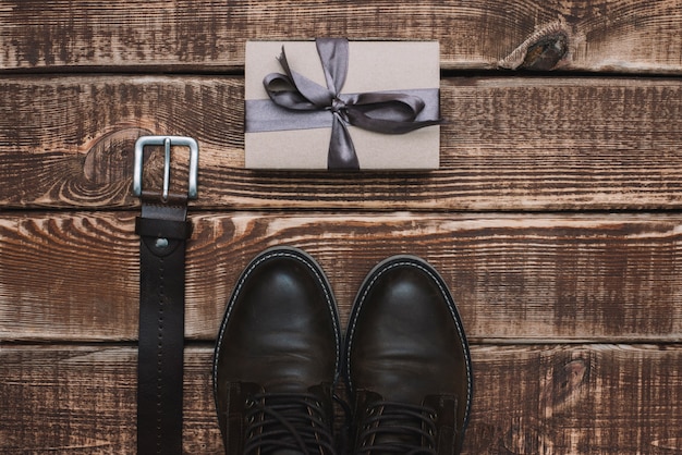 Gift box for father's day with men's accessories belt and leather shoes on a wooden table. Flat lay.