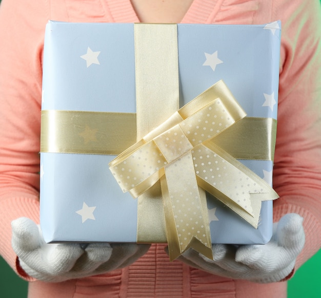 Photo gift box in female hand on color background