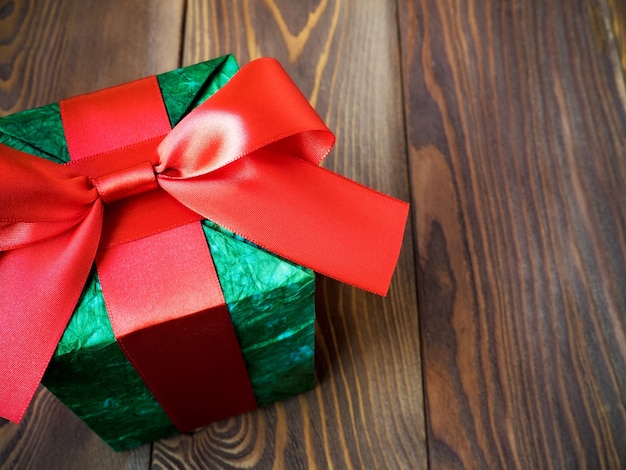 Gift box in glittery paper with bow on wooden board. Holidays concept