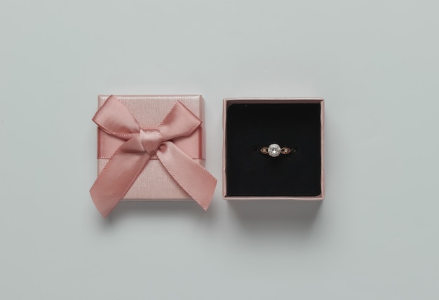 Gift box and gold ring with diamond on a pink pastel background. wedding concept. jewelry. top view. flat lay