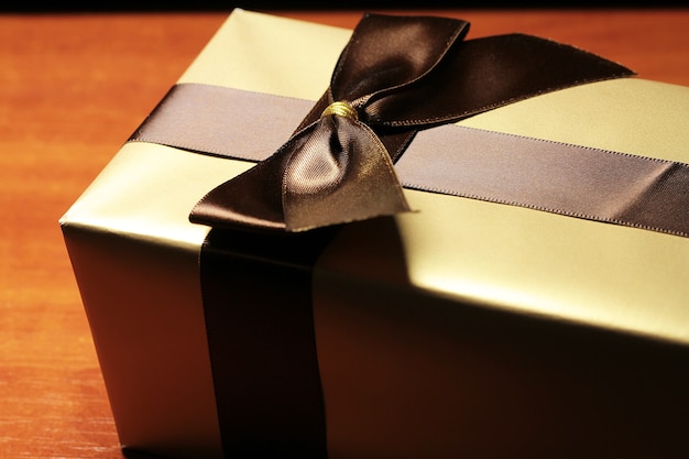 Photo gift box of golden color with brown ribbon