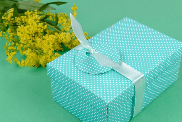 Gift box on green with yellow flower.