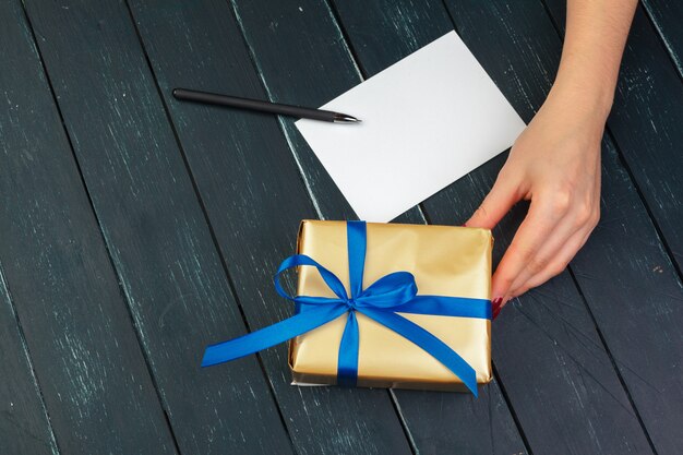 Gift box in hand girls on wood table