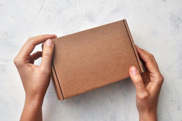 A gift box in the hands of a person with an empty label. Mockup