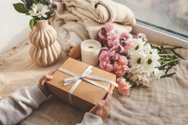 Photo gift box in hands with flowers at home