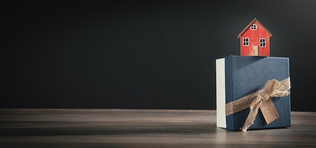 Gift box and house model on the wooden table.