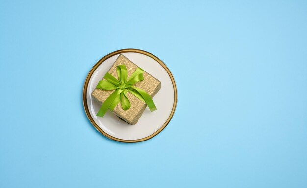 Gift box lies in a round plate on a blue background top view