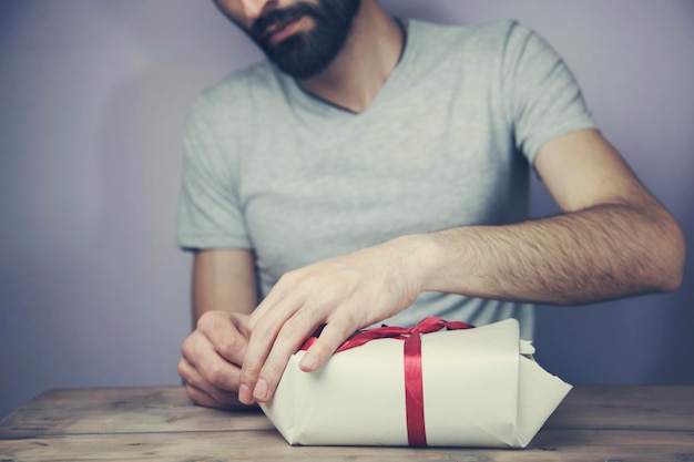 Gift box in man's hands on wooden table