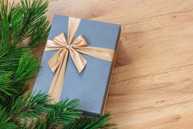 Gift box near christmas tree over wooden background