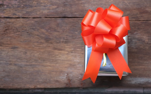 Подарочная коробка и оранжевый бант на деревянный стол на день Святого Валентина