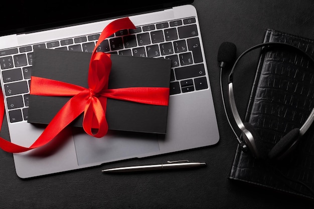 Фото Подарочная коробка над ноутбуком на столе в офисе верхний вид плоский с копировальным пространством концепция онлайн-покупки