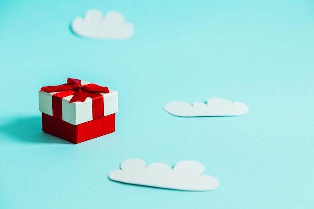 Gift box and paper clouds on a blue background