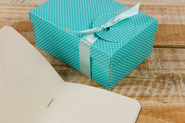 Gift box next to paper notepad on rustic wooden.