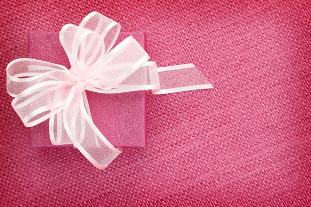 Gift box on pink fabric background