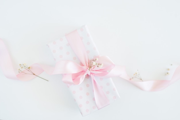 Confezione regalo in carta a pois, fiocco rosa, fiorellini. festa della donna