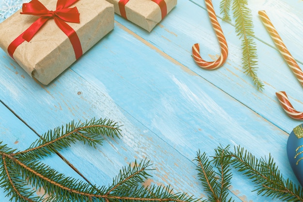 Gift box present wrapped, craft paper with red bow  with fur spruce pine coniferous branches, on the blue painted wooden background close up