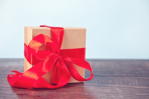 Gift box red bow on wood table. Copy space.