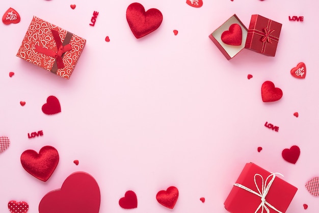 Confezione regalo e cuore rosso su sfondo rosa con copia spazio per il matrimonio d'amore o il giorno di san valentino.