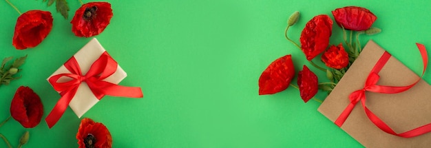 Gift box and red poppies on the green background Top view Copy space