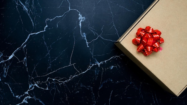 Confezione regalo nastro rosso su marmo nero vista dall'alto spazio copia