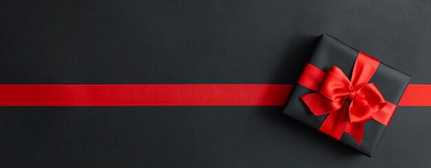 Gift box and red ribbon on black 