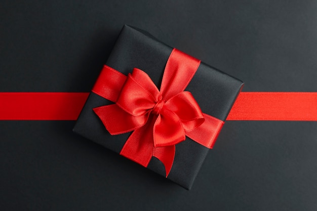 Gift box and red ribbon on black 