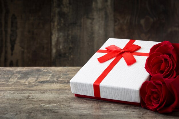 Gift box and red roses on wooden Valentines concept 