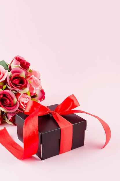 Confezione regalo, rose e cornice vuota su uno sfondo rosa