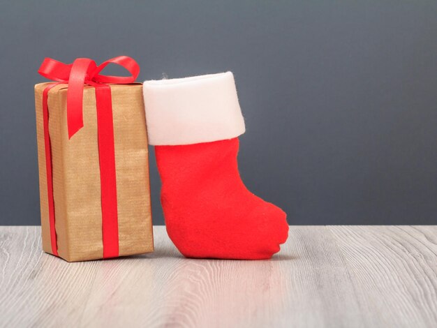 Gift box and Santa's boot on the gray background