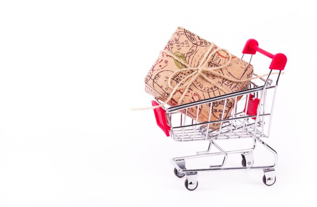 Gift box in shopping cart on white background.